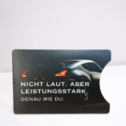 Dunkles Kartenmotiv mit silbernem Auto und leuchtenden Scheinwerfern und dem Wording "Nicht laut, aber leistungsstark. Genau wie du"